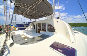 A sailboat with a covered deck area, a table, and a seating arrangement. - Sun-Kissed Sailing Adventure in Northern Croatia (Punat)