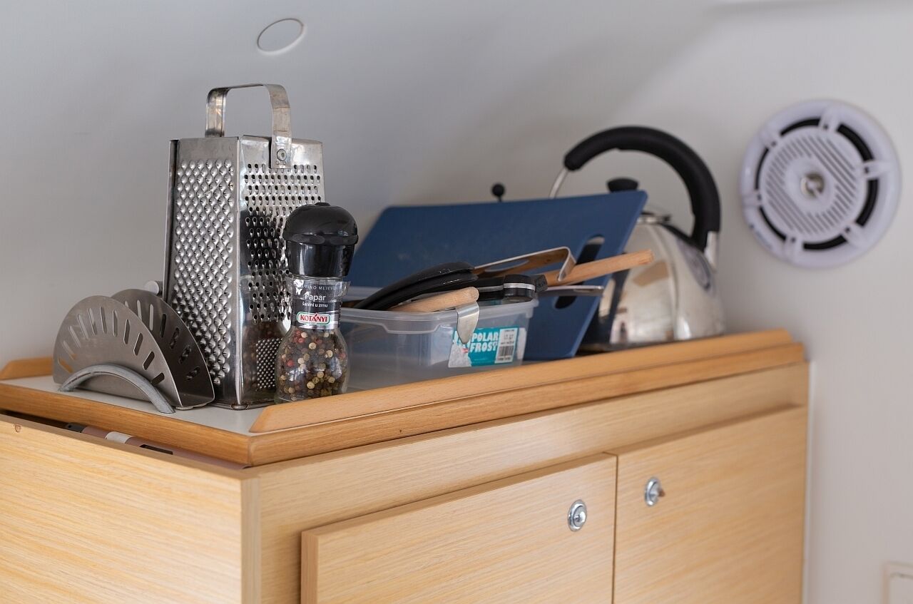 A kitchen counter with a grater, pepper mill, and a plastic container labeled 'Polar Frost.'