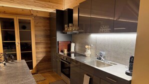 Une cuisine moderne dotée d’un four encastré, d’un évier en acier inoxydable et de meubles de rangement en bois.