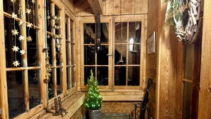 Un intérieur en bois avec de grandes fenêtres, un petit sapin de Noël et une décoration rustique.