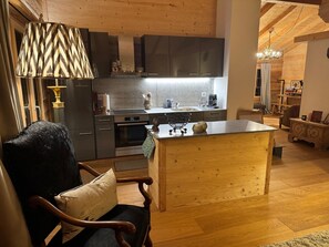 Een moderne keuken met houten kastjes, een centraal eiland en een eethoek met een houten stoel en tafel.