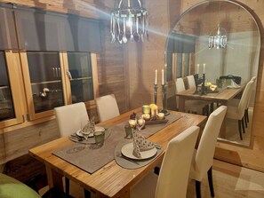 A dining area with a wooden table, chairs, candles, and a chandelier. - Heimersberg Appartement/Fewo, Bad, WC 3-Bettwohnung by Interhome (Zweisimmen)