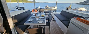 Comedor de un barco con una mesa dispuesta para dos, con platos, vasos y cubiertos.