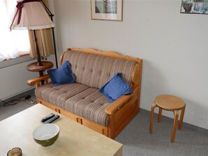 A wooden sofa with blue cushions, a small round table, a bowl, and a lamp. - Mireille Nr. 4 Appartement/Fewo, Dusche oder Bad, WC 4-Bettwohnung by Interhome (Gstaad)