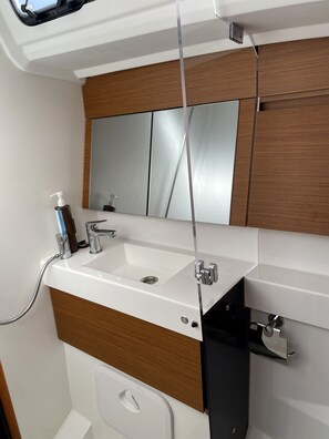 A bathroom with a white sink, a mirror, and a wooden vanity.