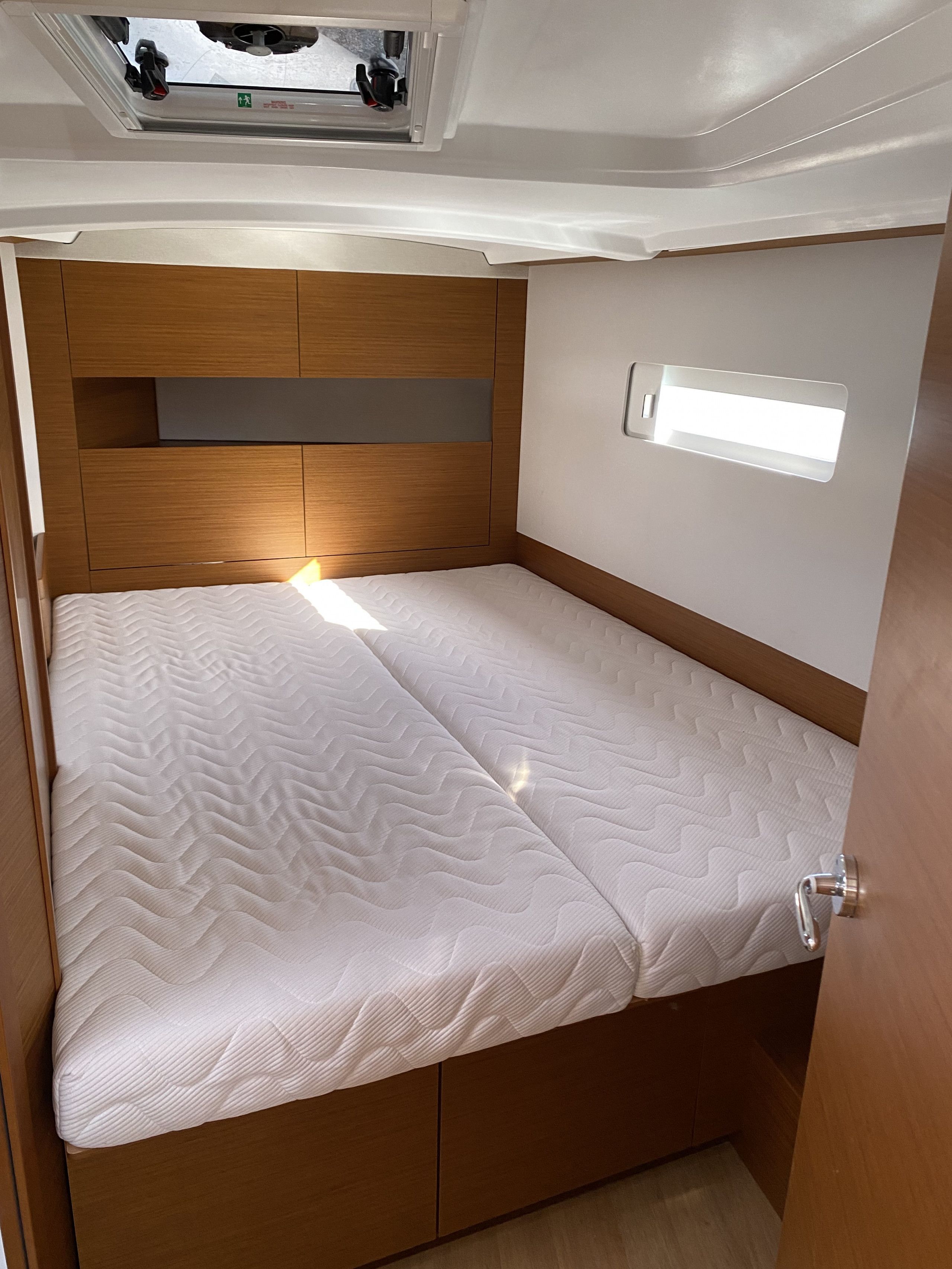 A compact bed with a headboard, a small window, and a door.