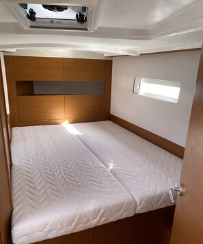 A compact bed with a headboard, a small window, and a ceiling light.