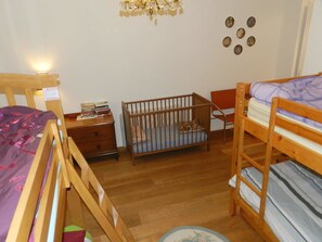 A child's room with bunk beds, a crib, a small table with books, and wall decorations. - Haus am Bach Appartement/Fewo, Dusche oder Bad, WC 8-Bettwohnung by Interhome (Zweisimmen)