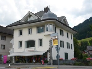 A large, two-story building with a prominent corner turret and a sign indicating nearby hotels. - Haus am Bach Appartement/Fewo, Dusche oder Bad, WC 8-Bettwohnung by Interhome (Zweisimmen)