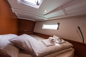 Een kamer met een bed, dakraam, klein raam en houten lambrisering.
