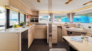 A compact kitchen with a view of the sea, a dining area, and a small seating space. - Sun-Kissed Sailing Adventure in Split, Croatia (Kaštel Gomilica)