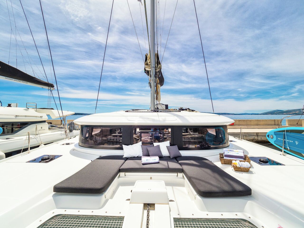 A yacht deck with a seating area, a mast, and other yachts in the background.