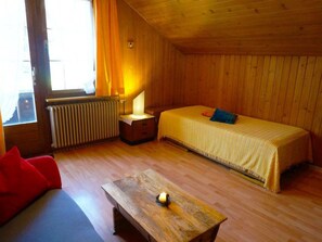 A room with a bed, a small table, a radiator, and a window with curtains. - Beatrice Appartement/Fewo, Dusche oder Bad, WC 3-Bettwohnung by Interhome (Zweisimmen)