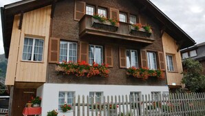 Un bâtiment à deux étages, avec un revêtement en bois et de nombreuses fenêtres, dont certaines sont dotées de volets.