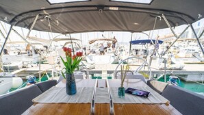 A boat deck with a table, two vases with flowers, and a person in the background. - Sun-Kissed Sailing Adventure in Split, Croatia (Kaštel Gomilica)