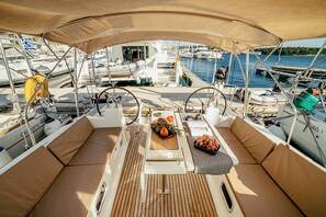 A boat deck with seating, a table with fruits, and a view of other boats in the marina.