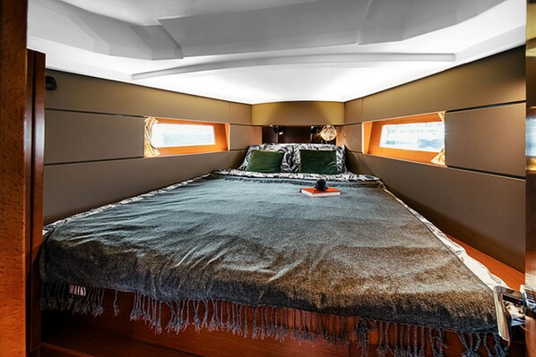 A bedroom with a large bed, two windows, and a ceiling with a skylight.