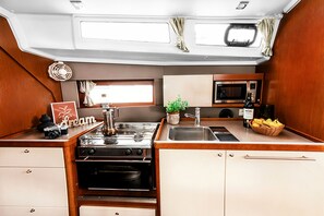 A compact kitchenette with a stove, oven, microwave, sink, and cabinets.