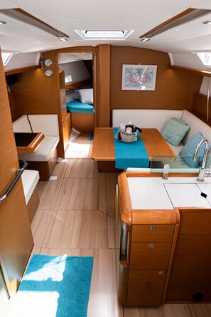 A compact boat interior with a kitchenette, a seating area, and a small bathroom. - Sun-Kissed Sailing Adventure in the Ionian Islands, Lefkada (Lefkada)