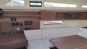 A boat interior with a wooden table, cushioned seating, a control panel, and windows. - Sun-Kissed Sailing Adventure in the Ionian Islands, Lefkada (Lefkada)