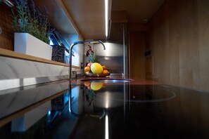 Uma cozinha moderna com uma pia de aço inoxidável, uma fruteira e um vaso de planta.
