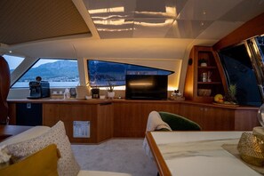 A modern interior with a kitchen area, a seating area, and a large window offering a view of the sea.
