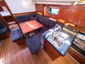 A compact kitchen with a sink, a dining area with a table and benches, and a small window. - Sun-Kissed Sailing Adventure in Northern Croatia (Punat)