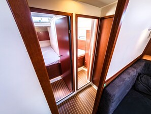 A compact, well-lit interior with a bunk bed, a small seating area, and a door leading to an adjacent room. - Sun-Kissed Sailing Adventure in Northern Croatia (Punat)