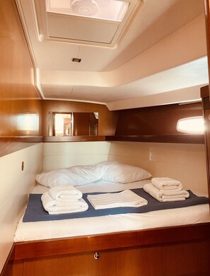 Ein kleiner Raum mit Bett, kleinem Fenster und Spiegel.