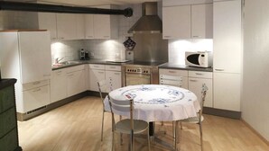 A compact kitchen with white cabinets, a stainless steel range hood, a microwave, and a dining table with chairs. - Studio Poli Studio, Dusche oder Bad, WC 2-Bettwohnung by Interhome (Zweisimmen)