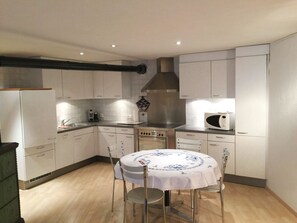 A compact kitchen with white cabinets, a stainless steel range hood, a microwave, and a dining table with chairs. - Studio Poli Studio, Dusche oder Bad, WC 2-Bettwohnung by Interhome (Zweisimmen)