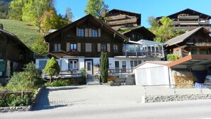 A traditional chalet-style building with a wooden facade, multiple balconies, and a ski lift visible in the background. - Studio Poli Studio, Dusche oder Bad, WC 2-Bettwohnung by Interhome (Zweisimmen)