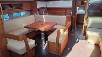Un intérieur compact et bien éclairé, avec une table centrale, des sièges rembourrés et un petit coin cuisine.