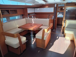 A compact, well-lit interior with a central table, cushioned seating, and a small kitchenette area. - Sun-Kissed Sailing: A Luxurious Beach Experience in Nikiti, Macedonia (Nikiti)