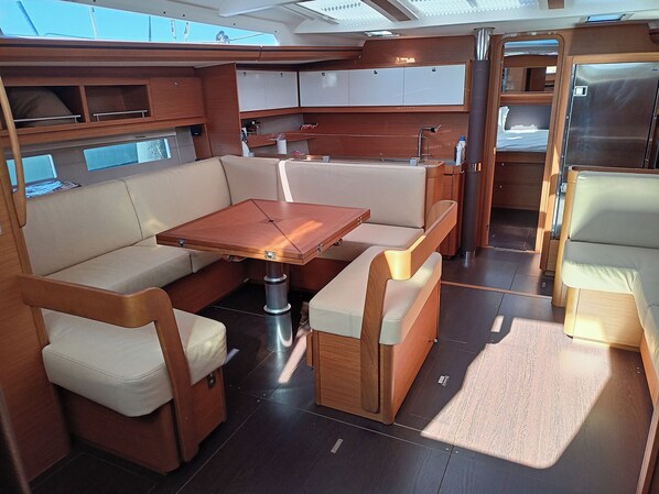 A compact, well-lit interior with a central table, cushioned seating, and a small kitchenette area.