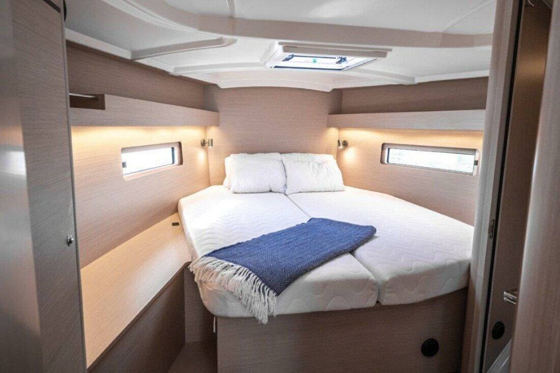 Ein kleines, helles Schlafzimmer mit Bett, Nachttischen und einem Oberlicht.