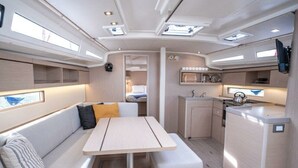 A compact interior with a dining area, kitchenette, and a small sleeping berth. - Sun-kissed Sailing Adventure in Istria, Croatia (Pomer)