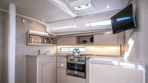 A compact kitchen with a built-in oven, a kettle, and a flat-screen TV mounted on the wall. - Sun-kissed Sailing Adventure in Istria, Croatia (Pomer)