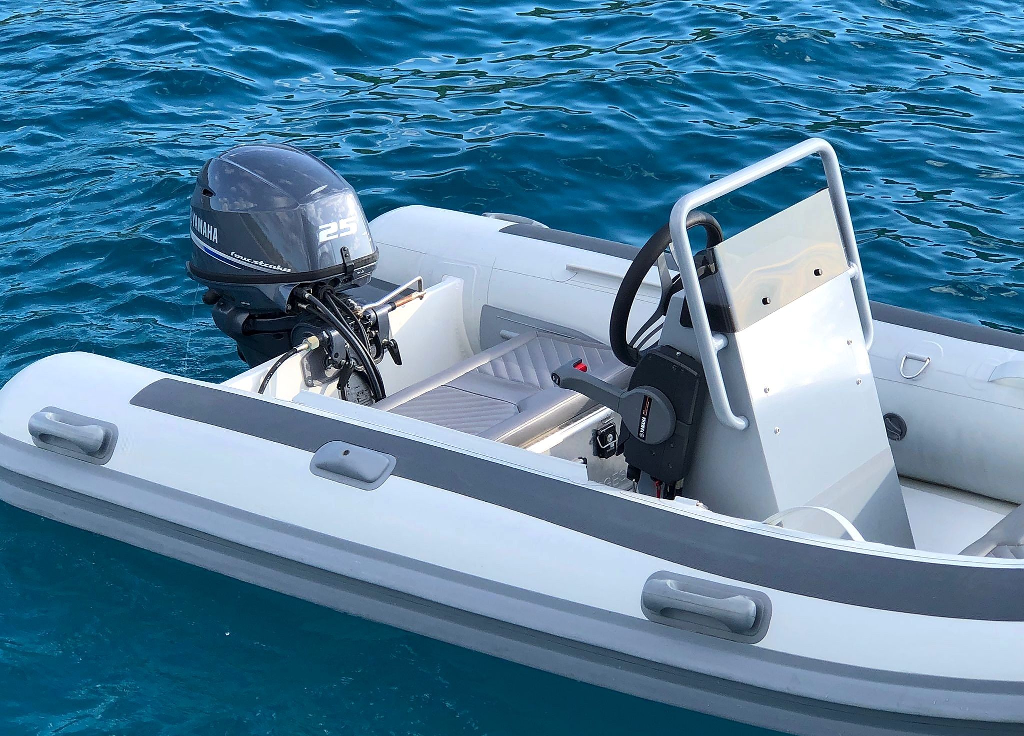 A small, white motorboat with a Yamaha outboard motor, a steering wheel, and a single seat.