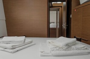 Ein Hotelzimmer mit einem ordentlich bezogenen Bett, einem Holzschrank und einem Spiegel, der den Raum widerspiegelt.