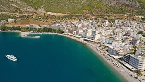 Vue aérienne d’une ville côtière avec un port de plaisance, des bâtiments et une plage.
