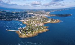 Vue aérienne d’une ville côtière avec un port de plaisance, des zones résidentielles et un phare.