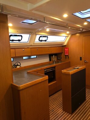 A compact galley with wooden cabinetry, a stove, and skylights.