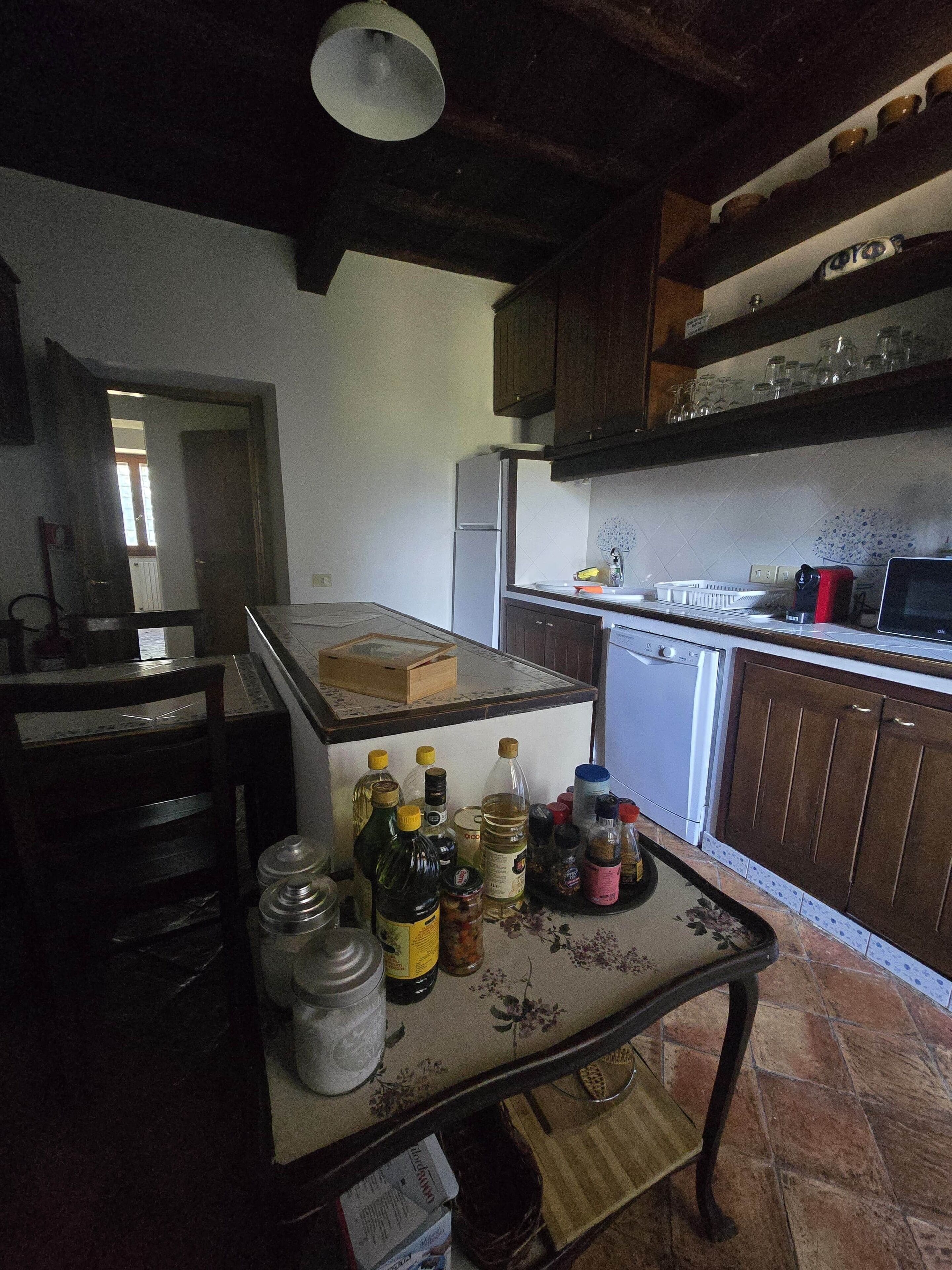 A kitchen with a refrigerator, a sink, and a table with various bottles and jars.