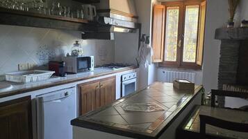 A kitchen with wooden cabinets, a tiled backsplash, a stove, and a window.