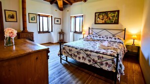 Ein Schlafzimmer mit einem hölzernen Bett, einer Holzkommode, einer Holzzieldecke und gerahmten Bildern an den Wänden.