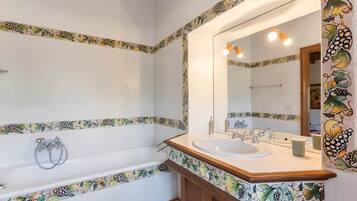 Un baño con bañera, lavabo y espejo.