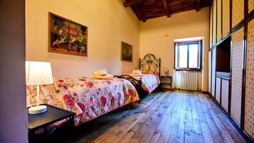 Un dormitorio con dos camas, un radiador, un ventanal y suelo de madera.