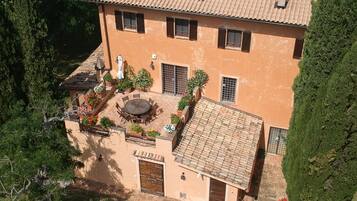 Un edificio con tetto in tegole, un cortile con tavolo e sedie rotonde, e una porta con la scritta 'LOFT'.