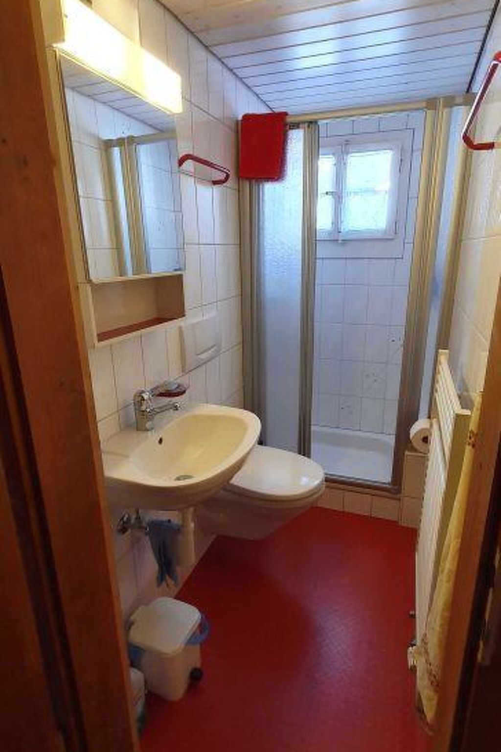 Et badeværelse med hvid vask, toilet og bruseområde.